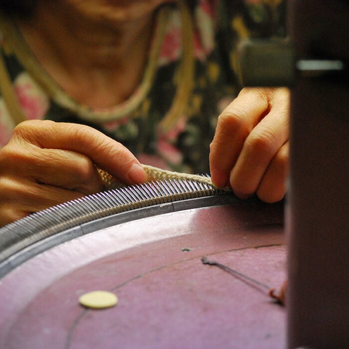 A vintage circular knitting machine being set up by its operator